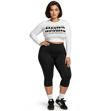 Woman wearing a white long-sleeve crop top with text and black leggings on a white background